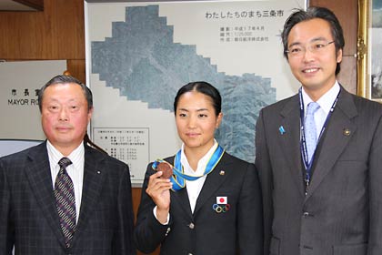 左から野崎体協会長、山田選手、国定市長