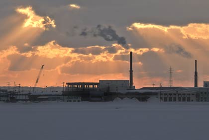 三条市西中付近から雪原の向こうに煙を上げる清掃センターの煙突