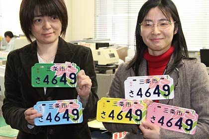 3月交付開始のオリジナルナンバプレートの見本を手に三条市の税務課職員