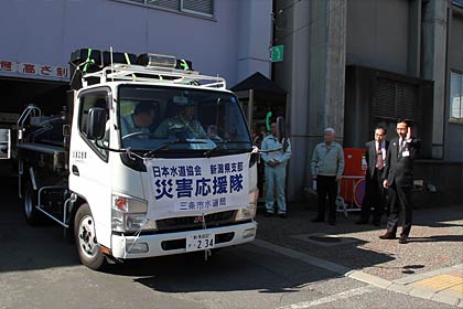 市役所を出発する給水車を見送る国定市長