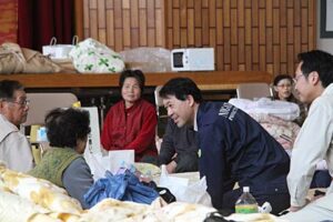三条市総合福祉センターで避難所生活を始めた福島県南相馬市の市民と話す泉田知事、その後ろは国定三条市長