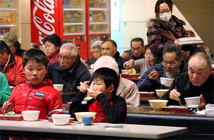  テーブルに着いて食事する避難者