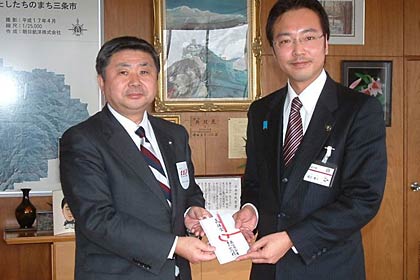  国定三条市長(右)に三条市内の避難所の運営に役立ててほしいと三条市への300万円を寄付を手渡す三条信用金庫の西潟理事長(左)