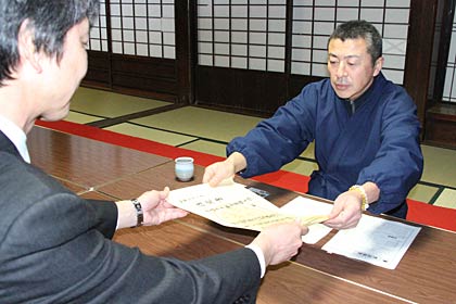 藤沢教育長(左)から指定署を受け取る山田住職(右)