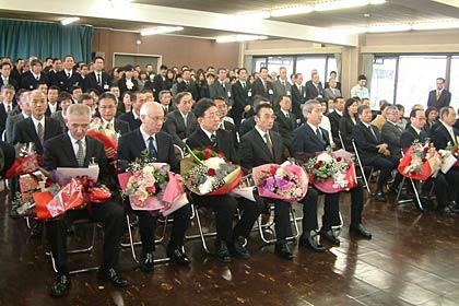 退職者が辞令書と花束を手に