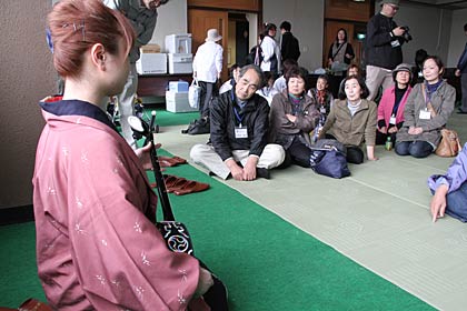 燕市に避難している70人近くが参加して24日行われた花見ツアー、分水福祉会館で三線を聴く