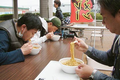発売前のもち入り三条カレーラーメンを味わう避難している人たち