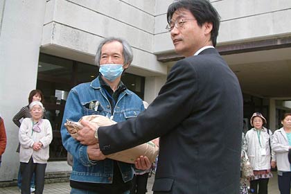 第1避難所リーダーだった佐藤賢二さんも帰宅、鈴木市長からコメを手渡す