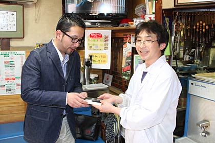 大黒亭松屋小路店で店主に著書を寄贈する相場さん