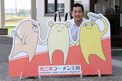 燕三条ラーメン王国のゆるキャラのパネルと代表の梨本さん