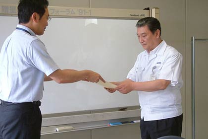 節電で休日シフトをスタートした野島製作所の柴沢常務(右)に節電応援隊の認定証を手渡す国定市長(左)