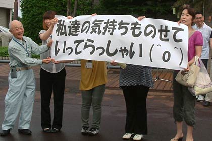 横断幕を掲げてボランティアを送り出す市社協職員
