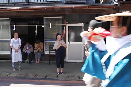 お年寄りは手を合わせて行列を迎える