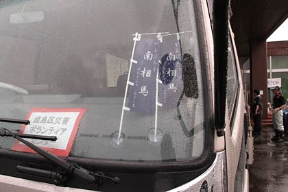 資材を積んだトラックのダッシュボードに「鹿島区災害ボランティアセンター」とある紙や「がんばろう南相馬」のミニのぼり旗