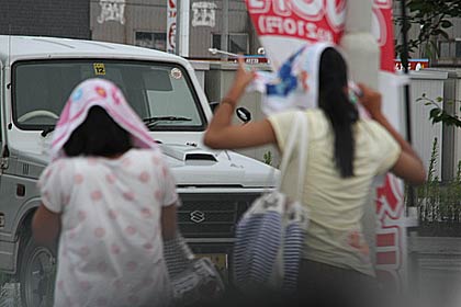市民プールの帰り道と思われる女の子が突然の雨で頭にタオルをかぶる