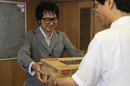 鈴木燕市長にカップ麺を手渡す「noanoa」の石橋店主