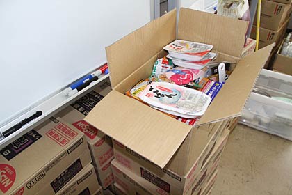 燕市被災者サポートセンターにある寄付されたたくさんの食品とともに石橋店主が寄付したカップ麺も避難している人たちに届けている