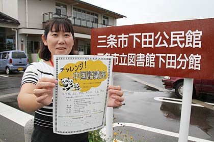 三条市下田公民館前でちらしを手に中国語講座の受講を呼びかける職員