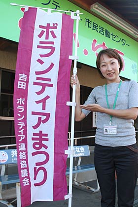 よしだ健康福祉ボランティアまつりで会場の燕市吉田産業福祉会館に立てるのぼりと来場を呼びかける事務局の燕市社会福祉協議会吉田支所職員