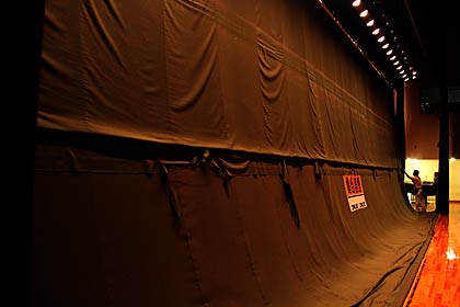 下の部分が落下した燕市吉田産業会館のステージの緞帳、写真の中ほどの高さの横にのびる部分の布が切れた