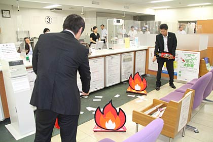 模擬犯人がガソリンに放った火を消火器で消し止める