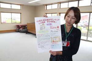 地域たすけ隊ボランティア養成講座の会場の燕市社会福祉協議会吉田支所でちらしを手にPRする職員
