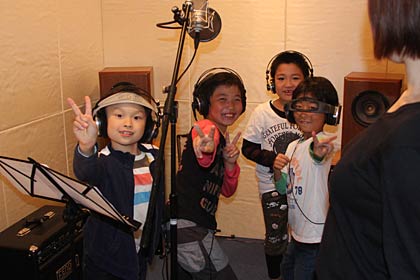 録音ブースのなかでリラックスする小学生た