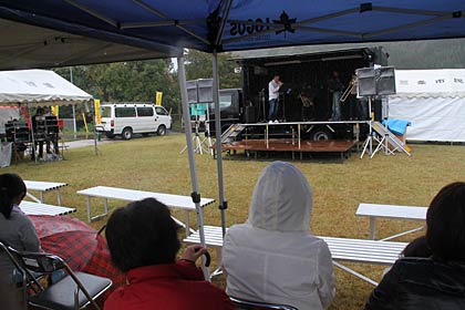 あいにくの雨降りで来場者はテントの下で雨をよけて見学