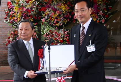 山崎金属工業からの金属洋食器の贈呈式で洋食器を国定市長(右)に洋食器を手渡す山崎社長(左)