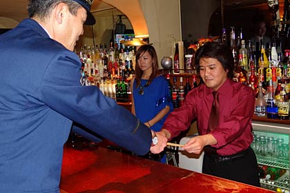 「ラスティ・ネール」で梨木店長にちらしを手渡す富岡三条署長
