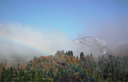 冠雪の山と青空を背景に虹もかかった