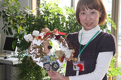  12月10日に開く「ピーナツサンタでXmasリースづくり」で作るクリスマスリースの見本、背景の観葉植物は「ボランティアグループみどり」が提供しているもの