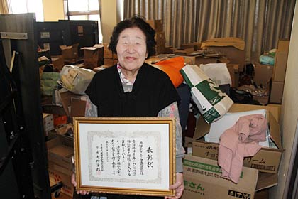 燕市社会福祉協議会の法人合併5周年福祉大会で燕地区ボランティア連絡協議会が受けた表彰状を手に竹野会長、後は企業から寄付を受けた物品