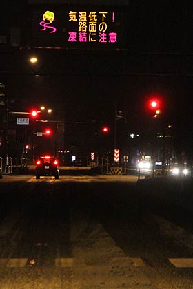 三条市上須頃地内の国道8号、路面に雪がシャーベット状に残り、道路の案内看板には路面の凍結に注意を呼びかける表示