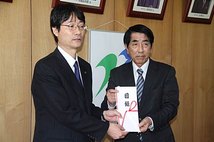 鈴木市長(左)に羽毛欠け布団20枚の目録を手渡す山下家具店の山下社長(右)
