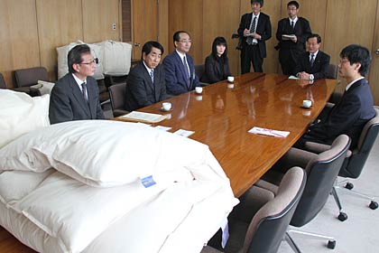 寄付した羽毛布団と左から山下家具店の佐藤営業企画部長、山下社長、ヤマシタ燕店の小武内店長