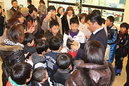 玄関ホールでファンに囲まれて気さくにサインにこたえる