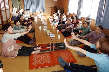 10日に小中川集会所で開かれた「地域のお茶の間『たっしゃらかね』」、岡村加奈さん作詞の曲『笑顔を忘れないで』にあわせたオリジナルの健康体操