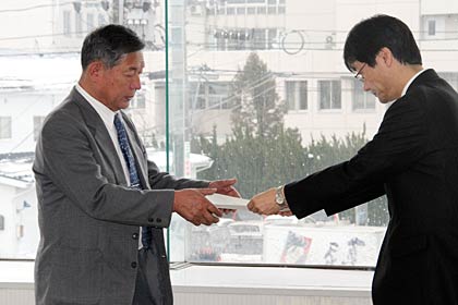 審議会会長に就いた泉谷吉田商工会会長(左)に諮問書を手渡す鈴木市長(右)