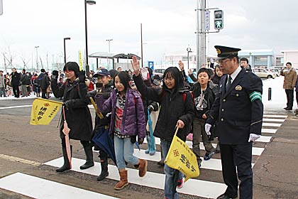 燕市立吉田南小学校正門前に新設された押しボタン式の信号機の点灯式と渡り初め式、手前右が児童を誘導する燕署の五十嵐署長
