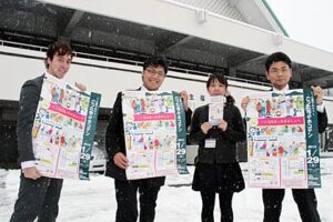 29日に1月の三条マルシェが開かれる三条市厚生福祉会館前でポスターを手に担当の地域経営課職員
