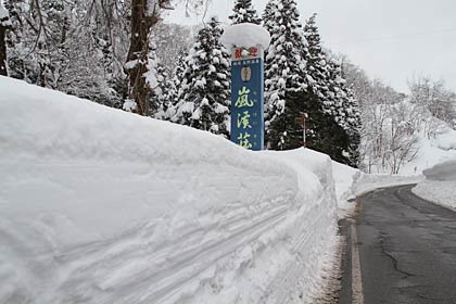 嵐渓荘前の県道鞍掛八木向線は平屋の屋根くらいの高さがある雪の壁