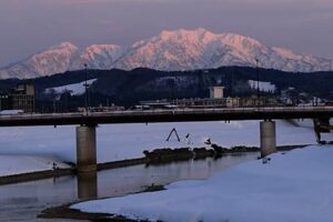 16日夕方、三条市の五十嵐川の向こうにピンクに染まって見えた粟ヶ岳