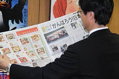 佐藤さん親子のグランプリをはじめコンテスト結果を伝える業界紙を広げる鈴木市長