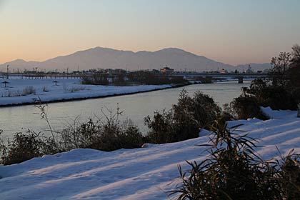  「うるう日」の29日、三条市上須頃地内の土手道路から中ノ口川と手前に河川敷の畑に覆う雪、向こうには弥彦山