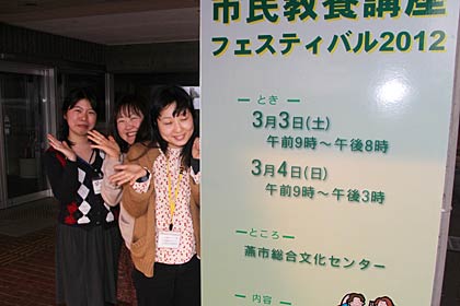 市民教養講座フェスティバル2012の看板の前で来場を呼びかける燕市中央公民館職員