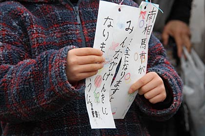 子どもの手に願いを込めて風船に下げた短冊