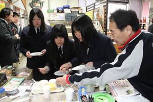 まちなか応援サポーターとして三条中心市街地エリア情報紙「まんなか」の取材で山重酒店を訪れた三条商業高校商業クラブの生徒3人、ひとまず取材より試食に熱中
