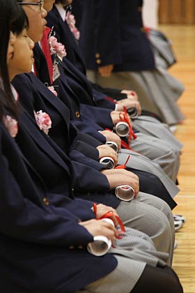 若井校長から受けた卒業証書を丸めてひざのうえに置く卒業生