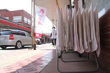  燕市燕地区の商店街の理容店の前で風に揺れるタオル